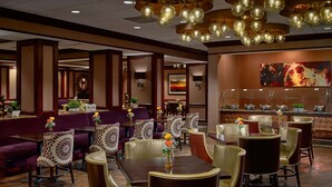 Un restaurant avec des tables et des chaises rondes, un coin bar et un plafond décoratif.