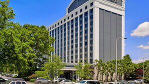 Un hôtel moderne, reconnaissable à son grand panneau « SONESTA », qui se distingue par sa façade symétrique, ses nombreux étages et son parking rempli de voitures.