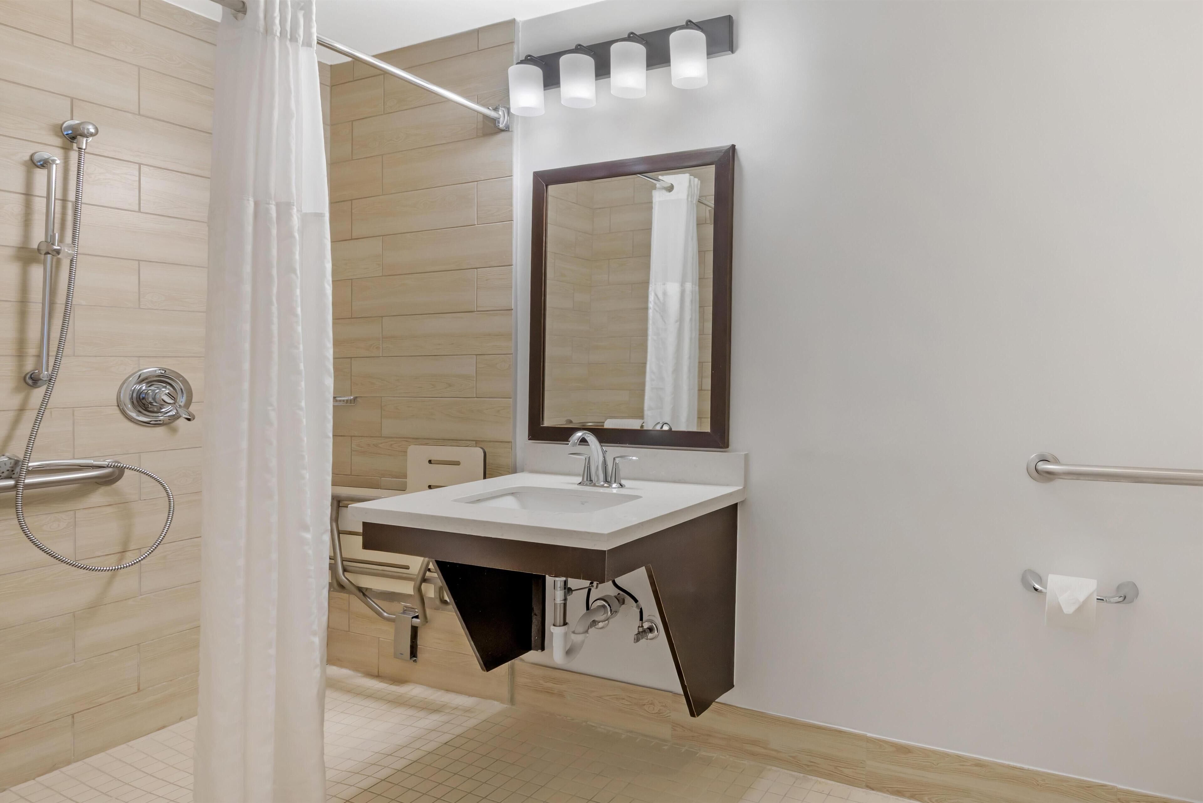 Une salle de bain moderne avec une douche, un lavabo et un miroir.