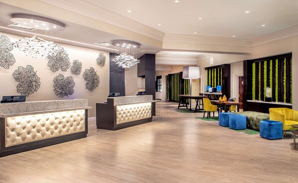 Um hall de hotel moderno com balcão de recepção, área de estar e arte decorativa na parede.