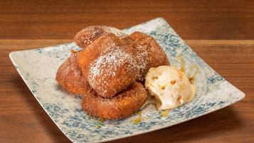 A plate of fried doughnuts with powdered sugar and a scoop of vanilla ice cream.