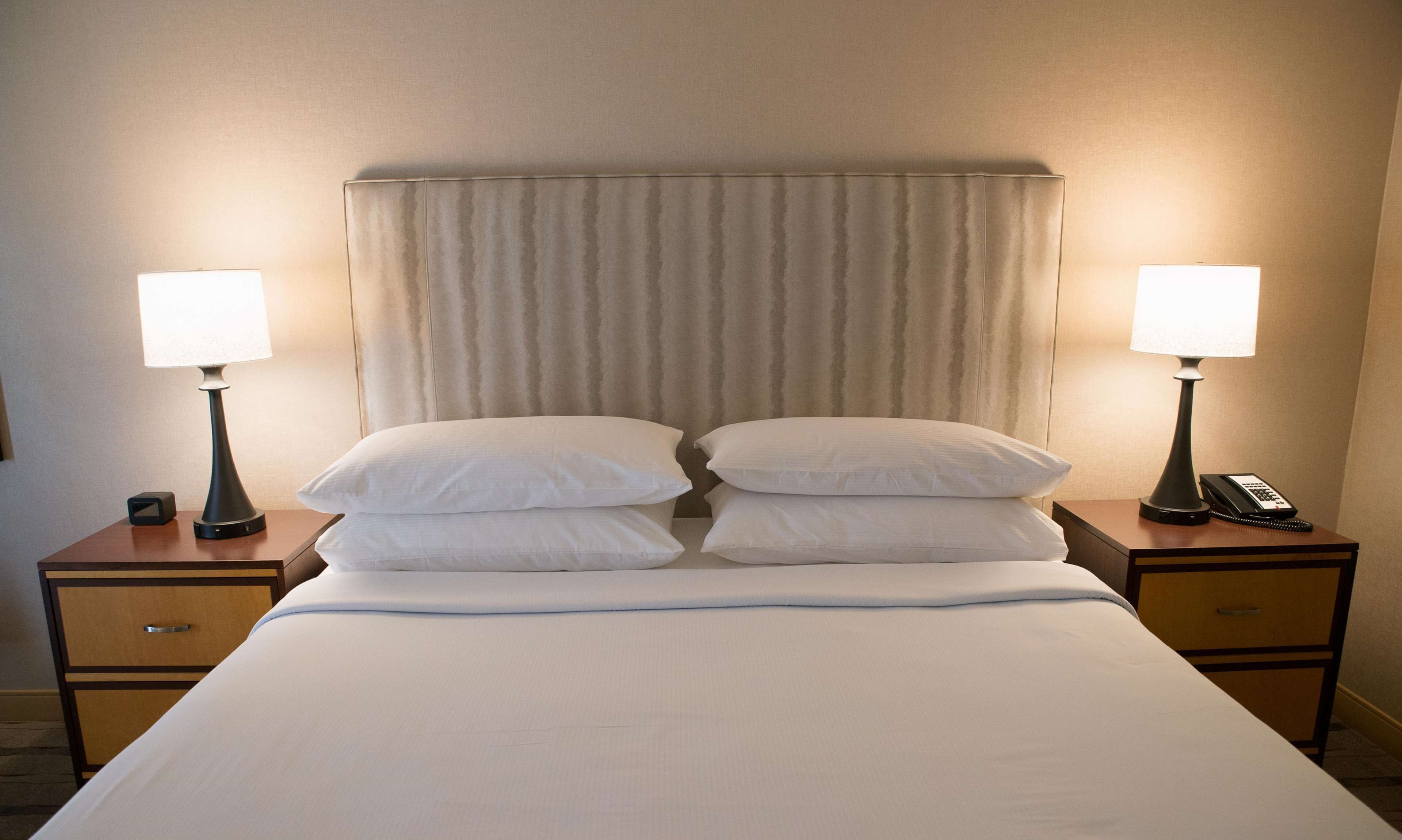 A hotel room with a bed, two bedside tables, two lamps, and a telephone on one of the tables.