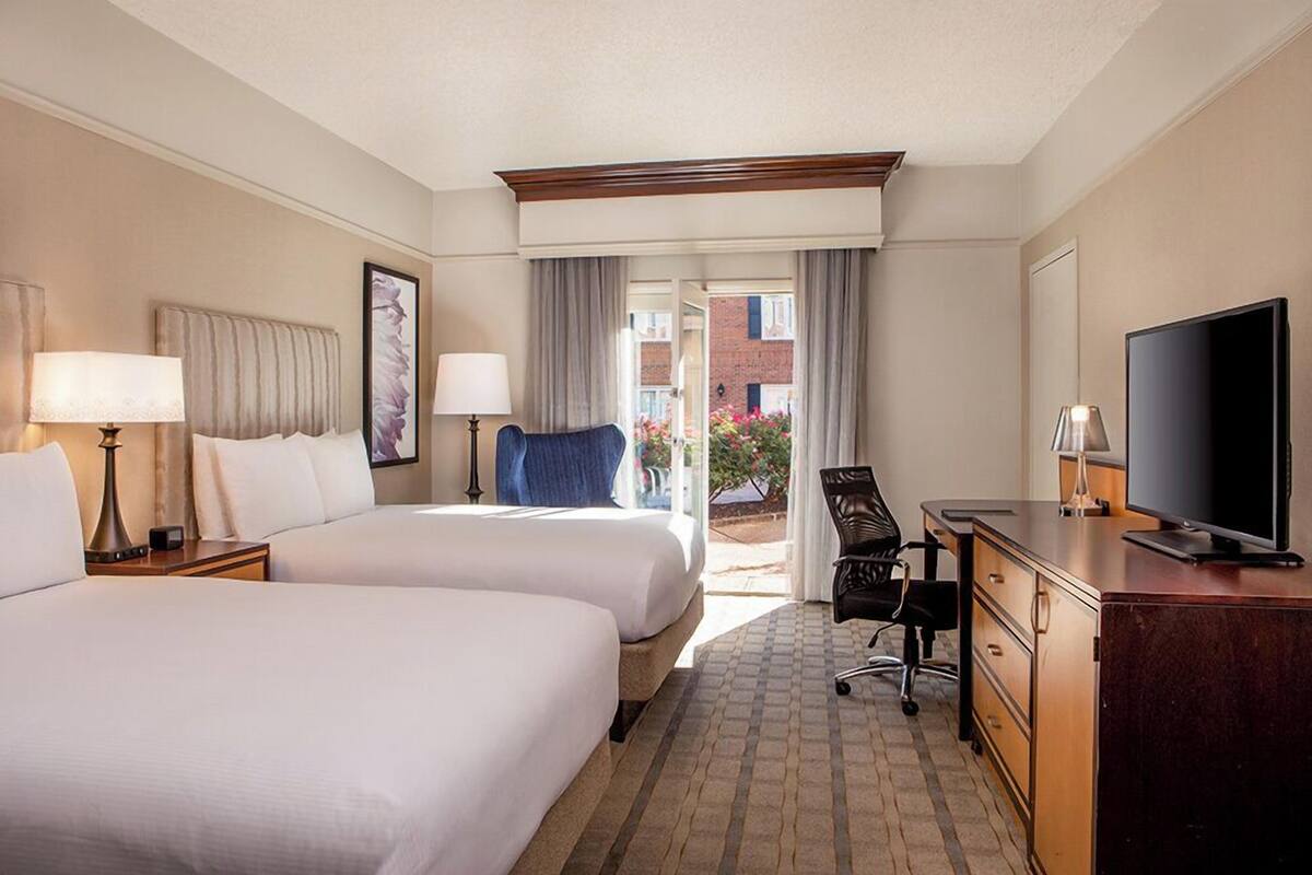 Een hotelkamer met twee bedden, een bureau, een televisie en uitzicht.