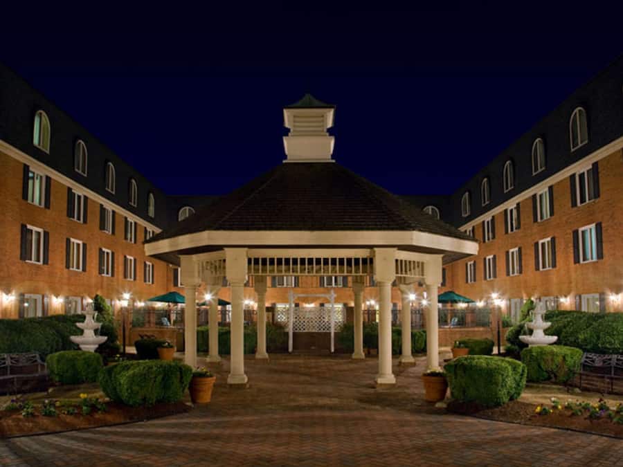 A courtyard with a gazebo, brick buildings, and well-maintained hedges.