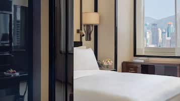 A hotel room with a bed, a desk, a lamp, a window with a city view, and a TV.