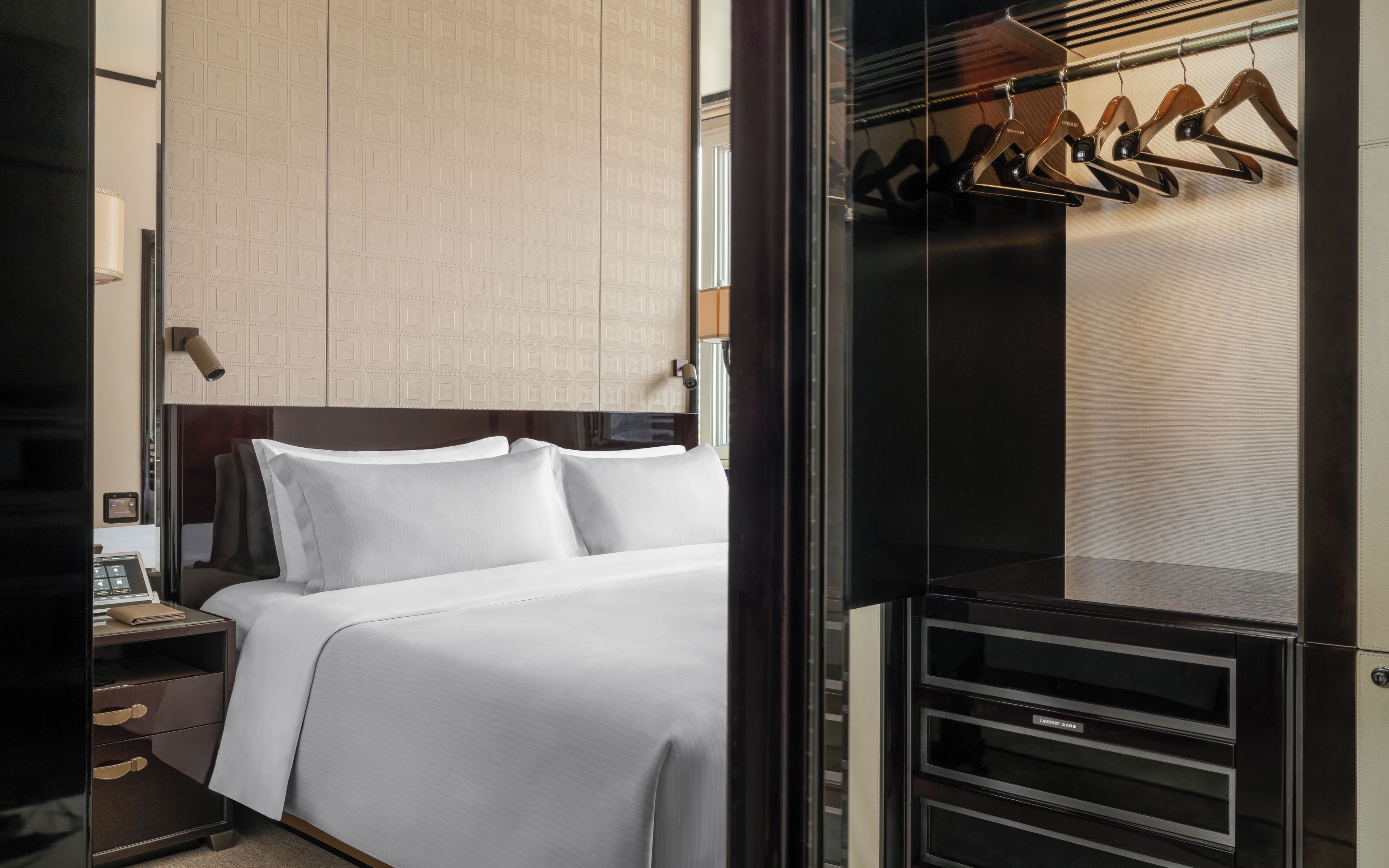 A hotel room with a bed, a nightstand, a wardrobe, and a mirror.
