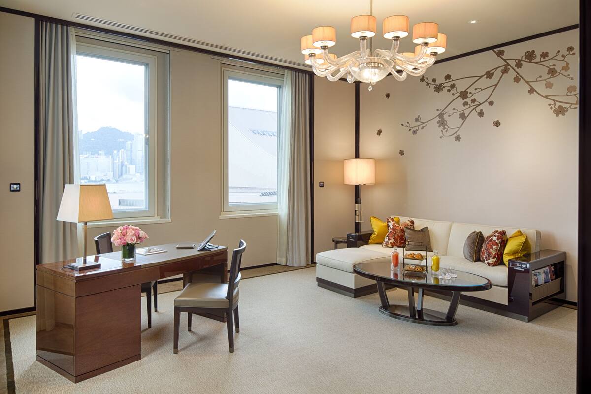 Una habitación de hotel con escritorio, silla, sofá, mesa de centro y candelabro.