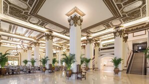 A grand lobby with ornate columns, chandeliers, and a polished floor. - The Peninsula Hong Kong (Kowloon)
