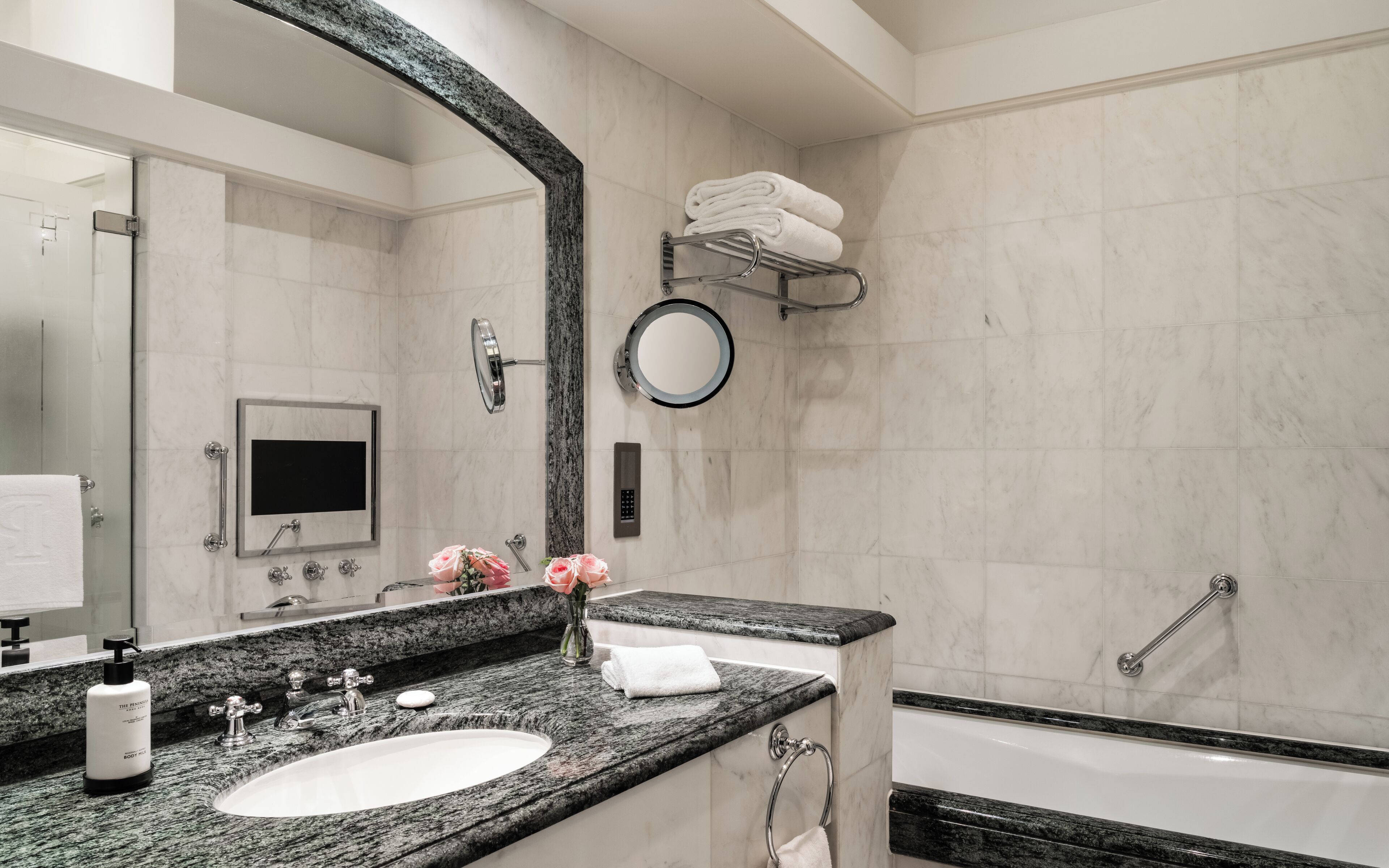 Une salle de bain avec un grand miroir, un lavabo, un meuble-lavabo, une baignoire et un porte-serviettes.