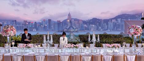 A table set for a formal event with a city skyline view, including a prominent tower.