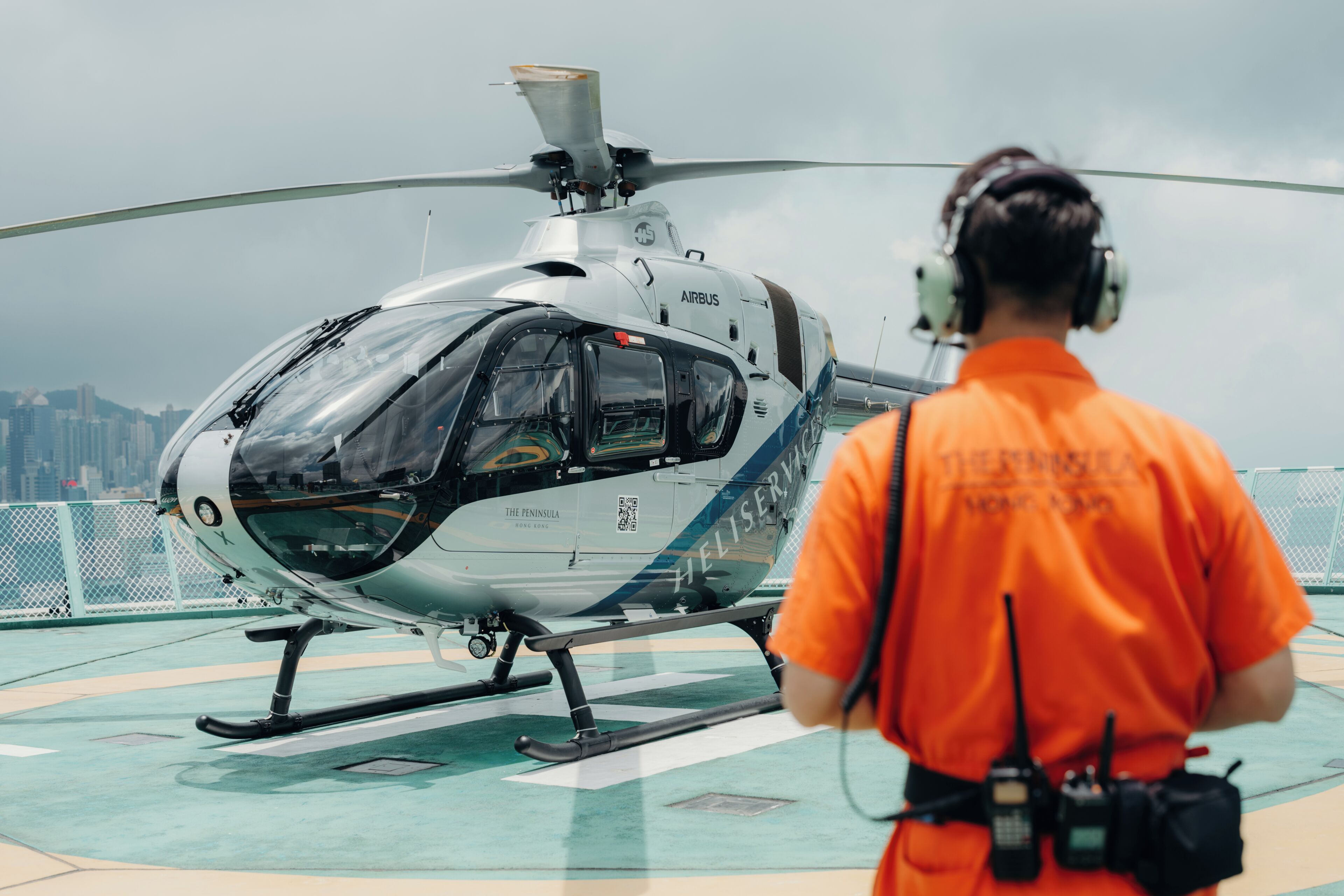 A helicopter on a helipad with a cityscape in the background.