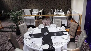 A dining area with round tables set for four, each with white tablecloths, silverware, and glassware. The room has patterned wallpaper and a potted plant. - Hylands Hotel (Coventry)
