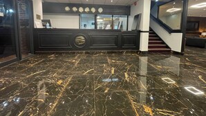 A lobby with a black reception desk, a marble floor, and a staircase. - Hylands Hotel (Coventry)