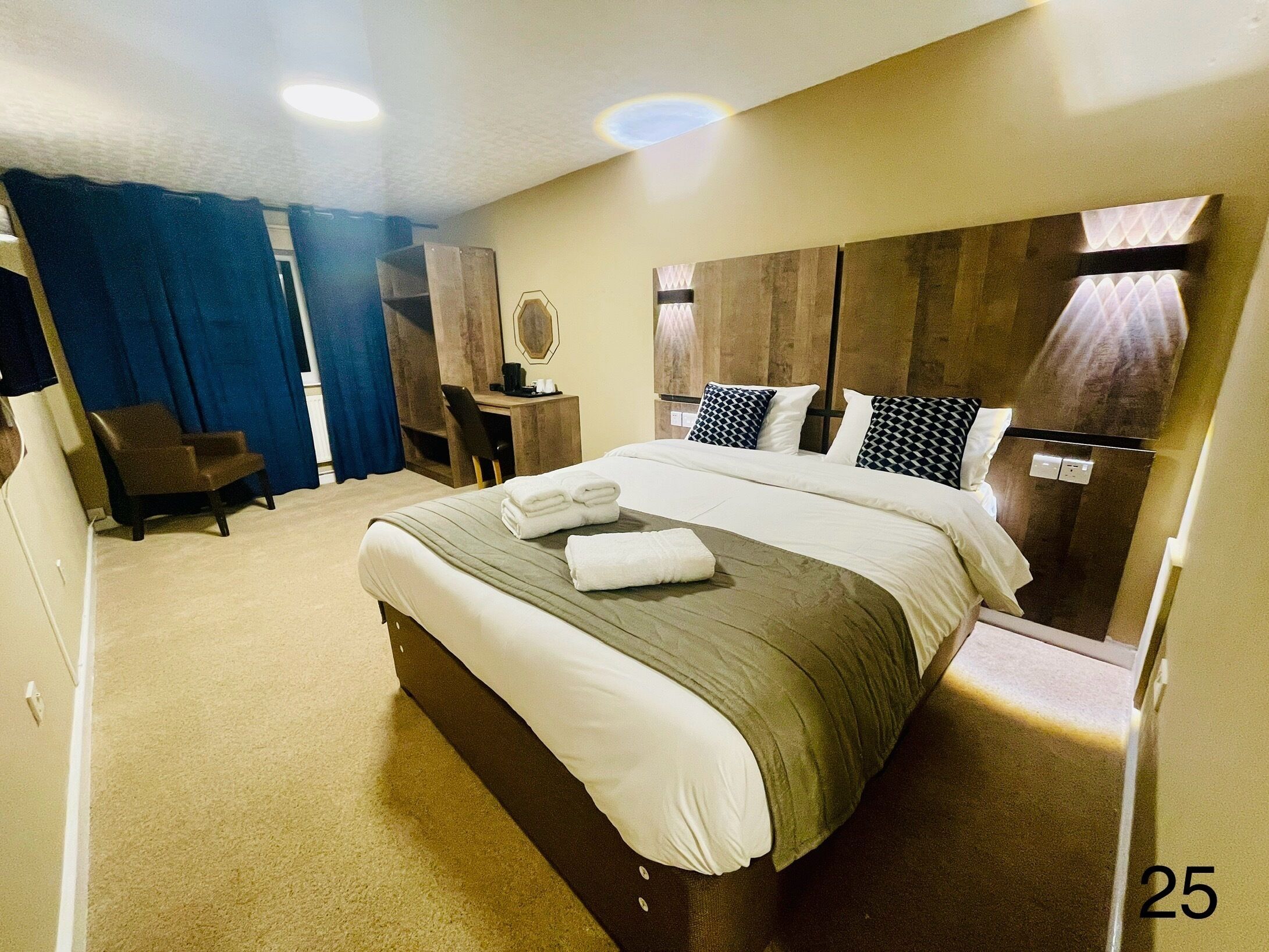 Quarto de hotel com cama grande, escrivaninha, cadeira e guarda-roupa.