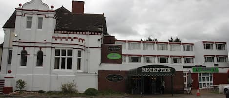 Un hotel con una zona de recepción, un cartel que dice 'The Hylands Hotel' y un letrero de 'Jeera'.