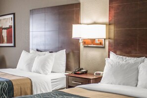A hotel room with two beds, a nightstand with a lamp, a phone, and a painting on the wall.