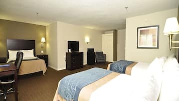 A hotel room with two beds, a desk, a chair, a TV, a dresser, and a lamp.