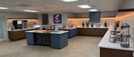 A hotel lobby with a central reception desk, a Comfort Inn sign, and a counter with various items.