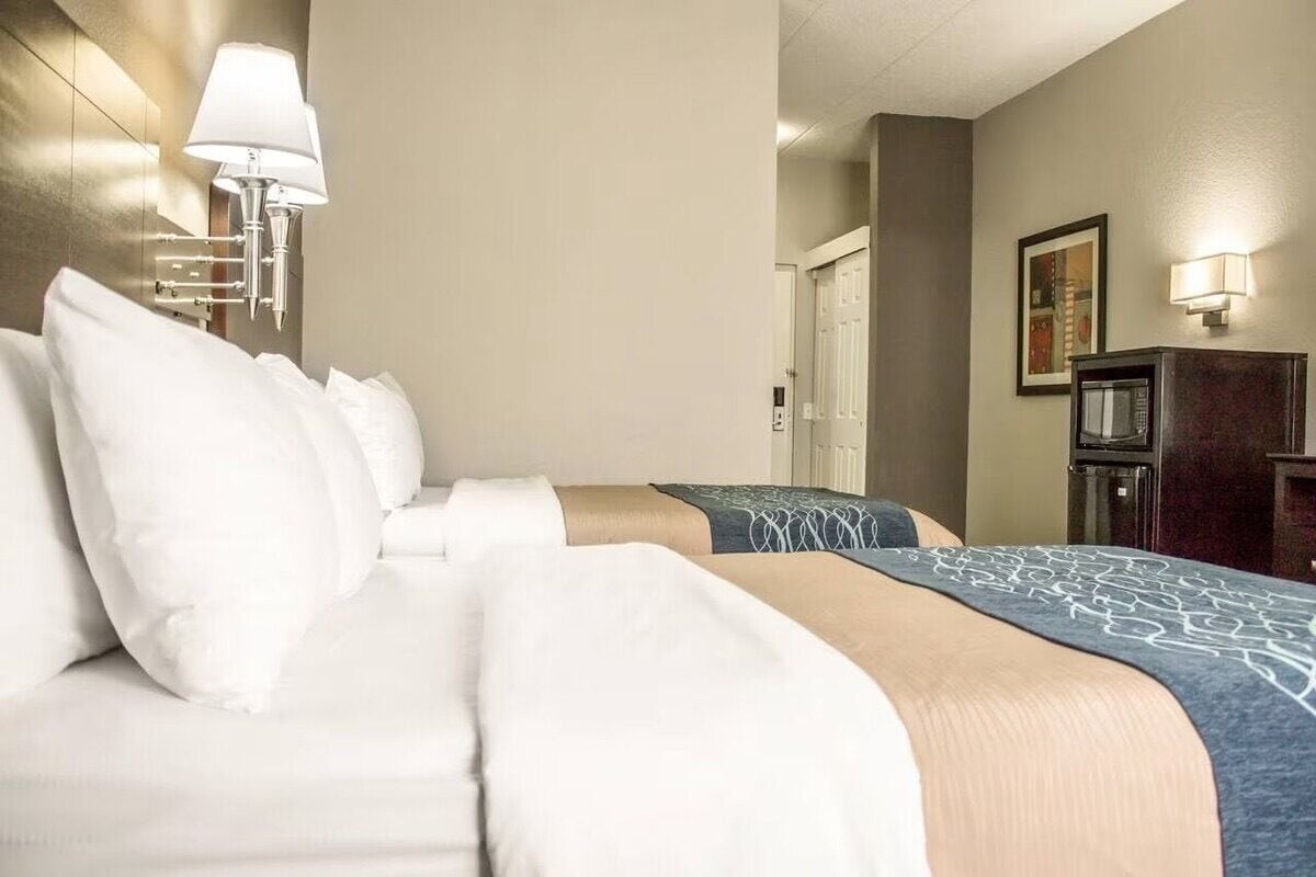 A hotel room with a bed, a desk, a lamp, and a television.