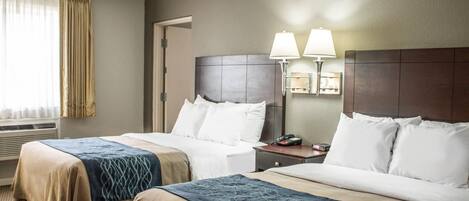 Habitación de hotel con dos camas, una mesita de noche, una lámpara y una ventana con cortinas.