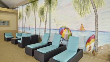 Relax in a lounge area with wicker chairs and a vibrant mural of a beach scene.