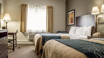 A hotel room with two beds, a desk, a chair, a telephone, and a window with curtains.