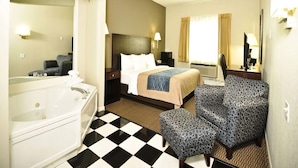 Une chambre d’hôtel avec un grand lit, un coin salon séparé, une salle de bain avec baignoire et un sol à carreaux.