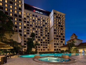 Un hôtel comprenant plusieurs étages, une piscine et des espaces de détente en plein air.