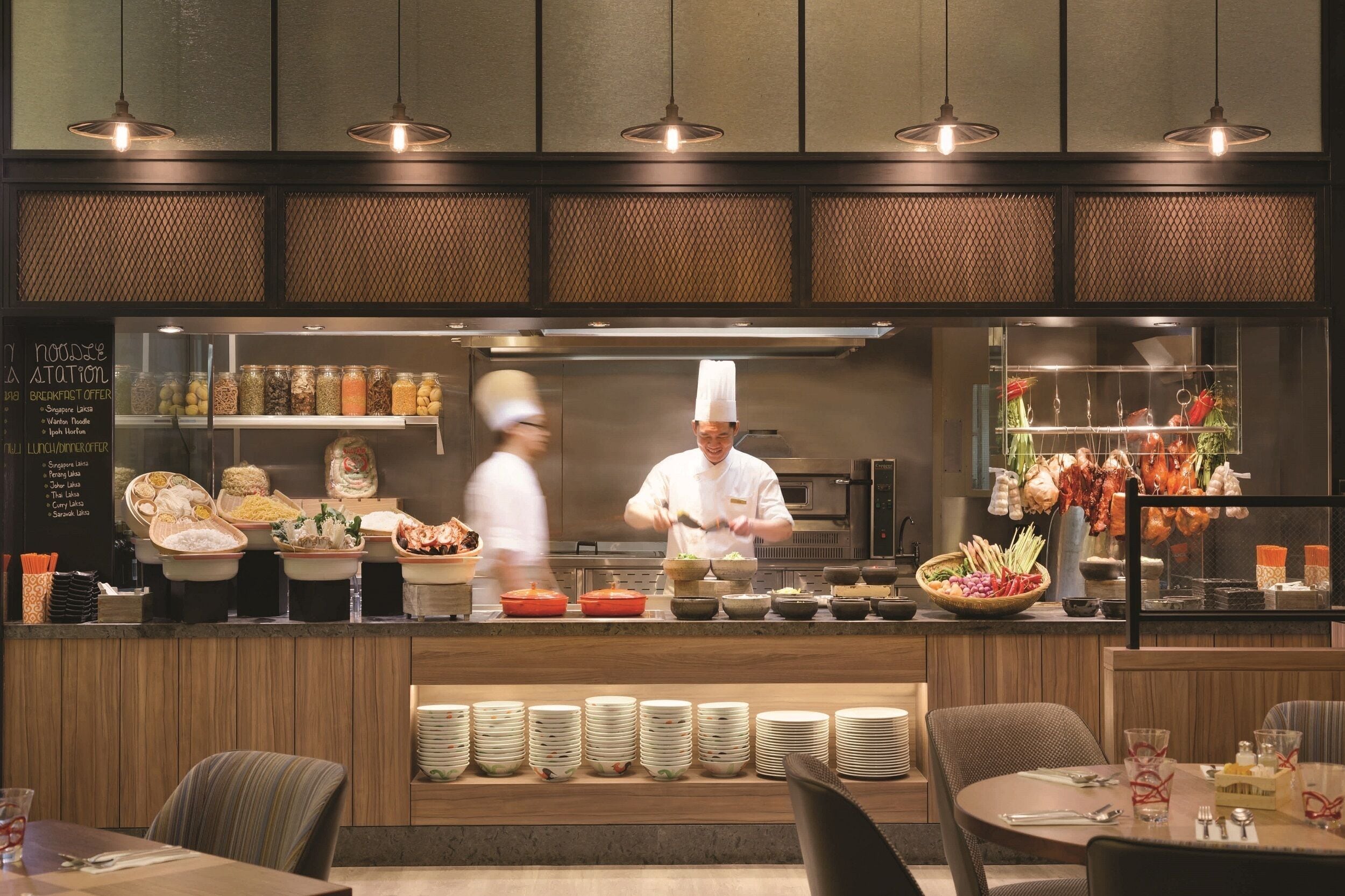Un restaurante con una barra de buffet, un chef preparando comida y una variedad de platos a la vista.
