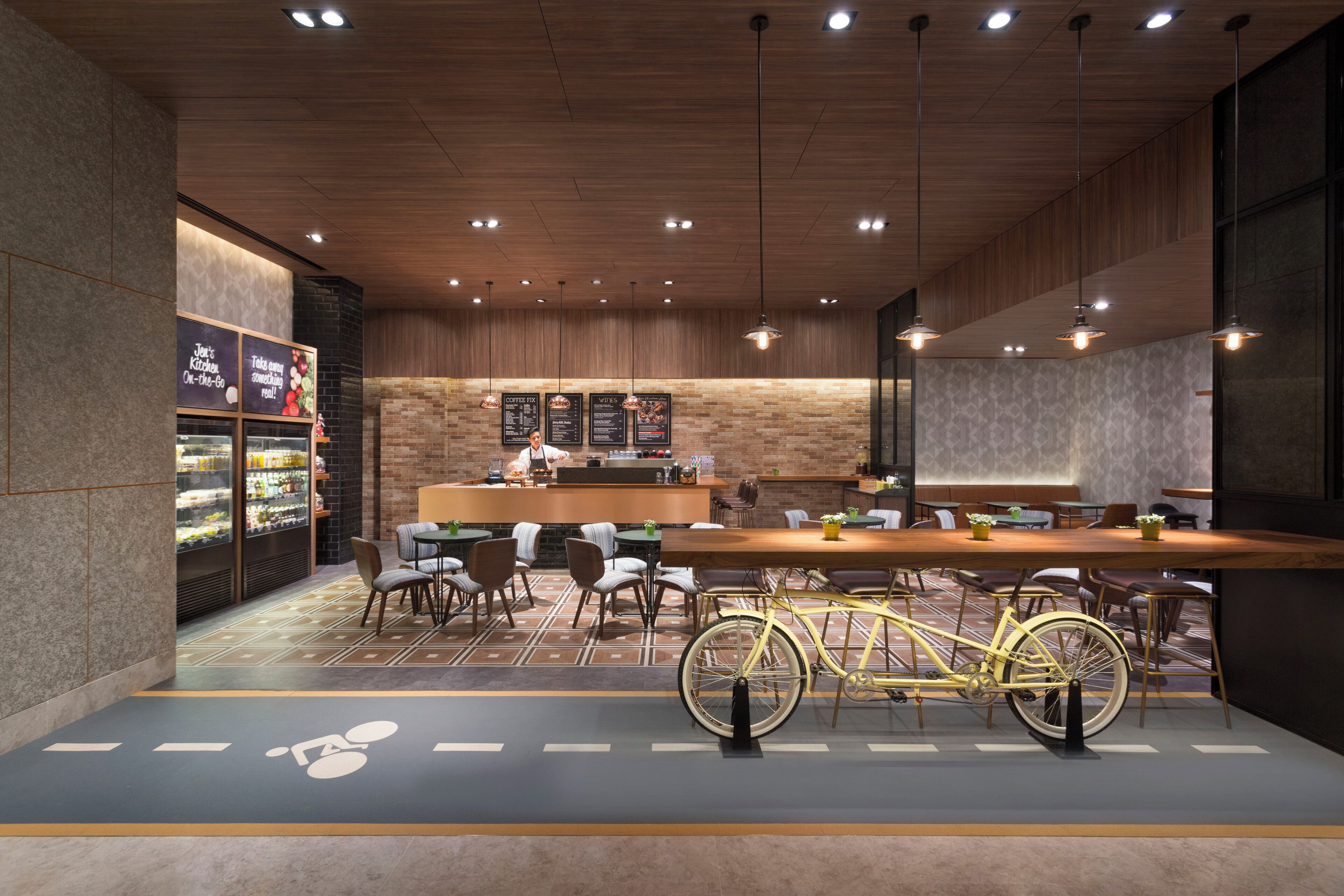 Una cafetería moderna con techo de madera, una bicicleta y un área de estar con mesas y sillas.