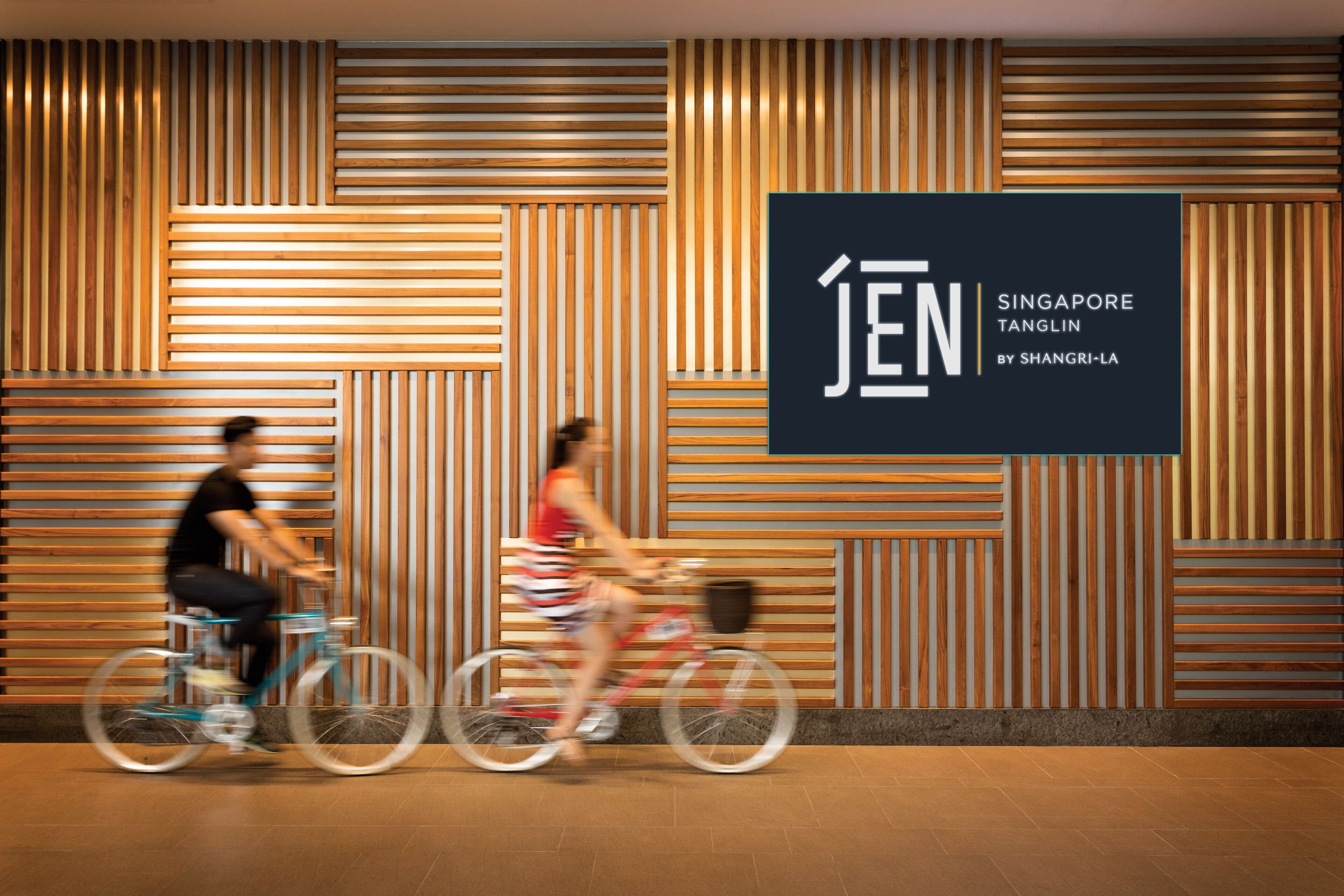 Un interior moderno con listones de madera en las paredes y un gran cartel que dice 'JEN Singapore Tanglin by Shangri-La'.