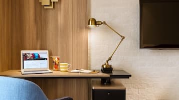 Un espace de travail moderne équipé d’un ordinateur portable, d’une lampe de bureau et d’un téléviseur fixé au mur.