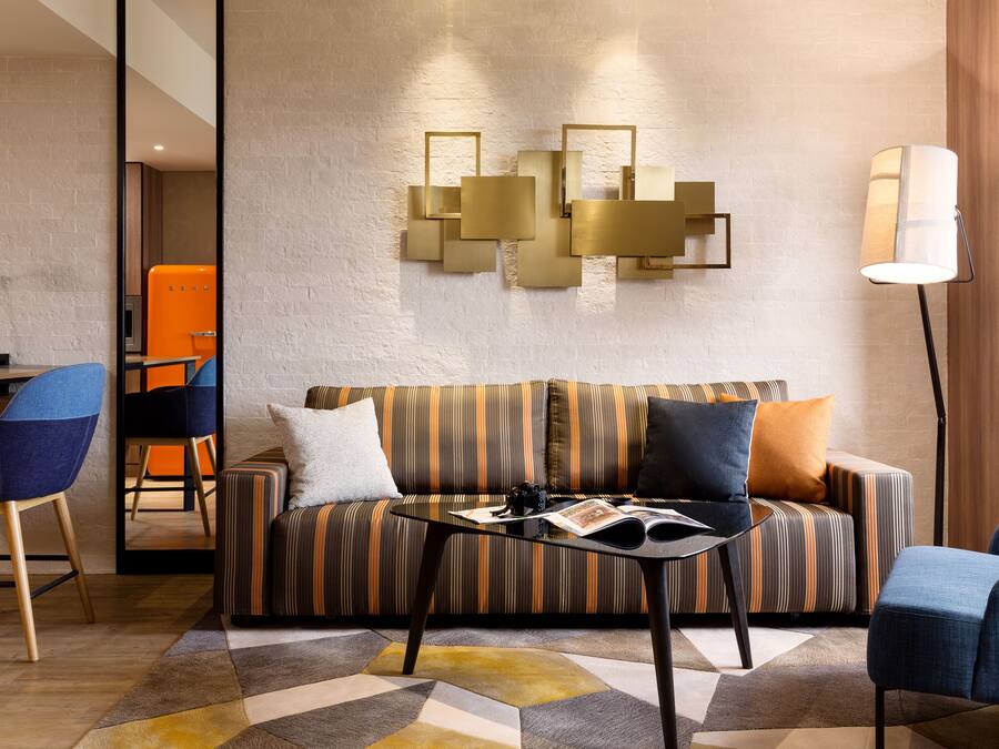 A modern living room with a striped sofa, a glass coffee table, and a floor lamp.