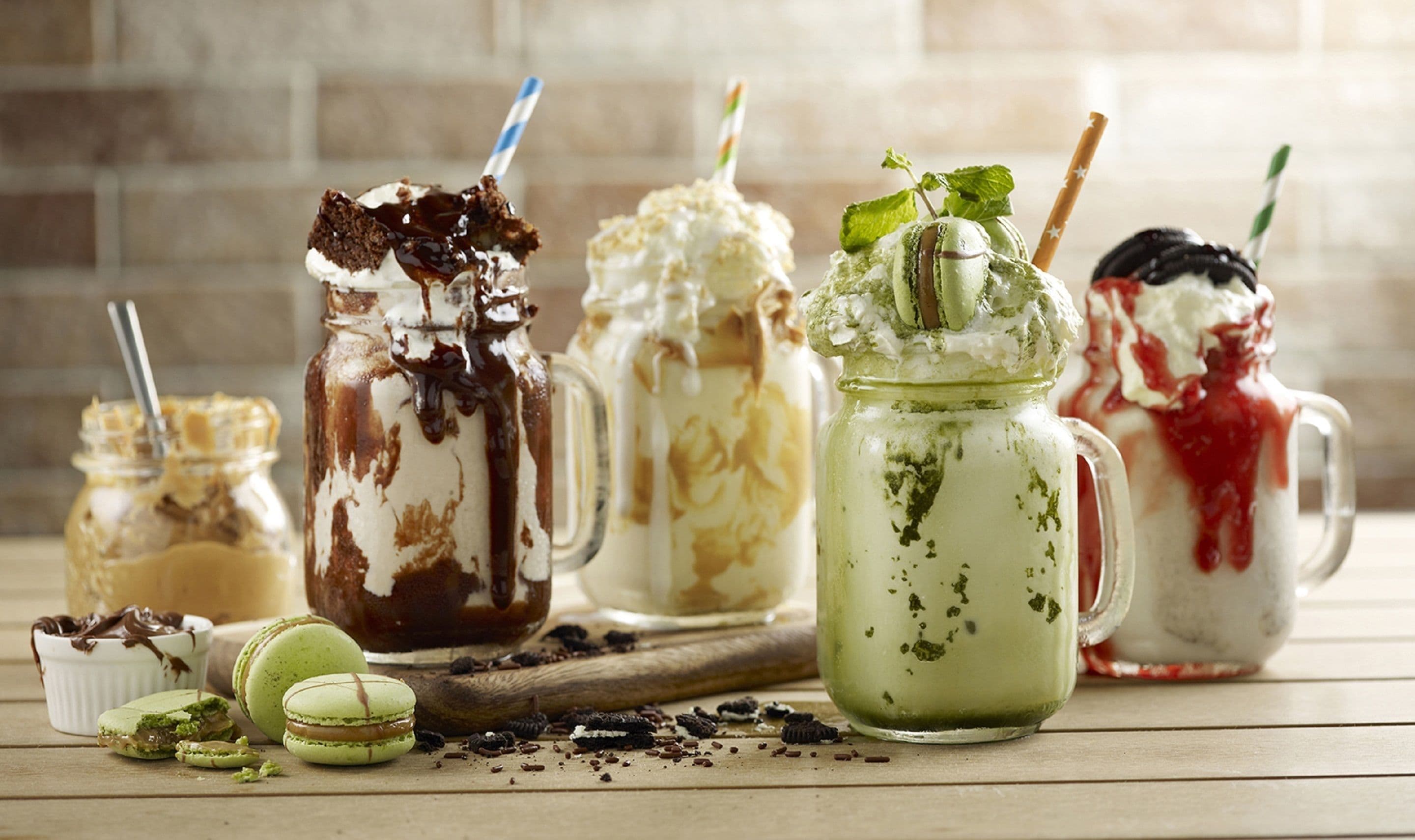 Une variété de desserts présentés dans différents récipients, notamment une boisson verte au matcha, un dessert au chocolat avec de la crème fouettée et un dessert rouge également accompagné de crème fouettée.