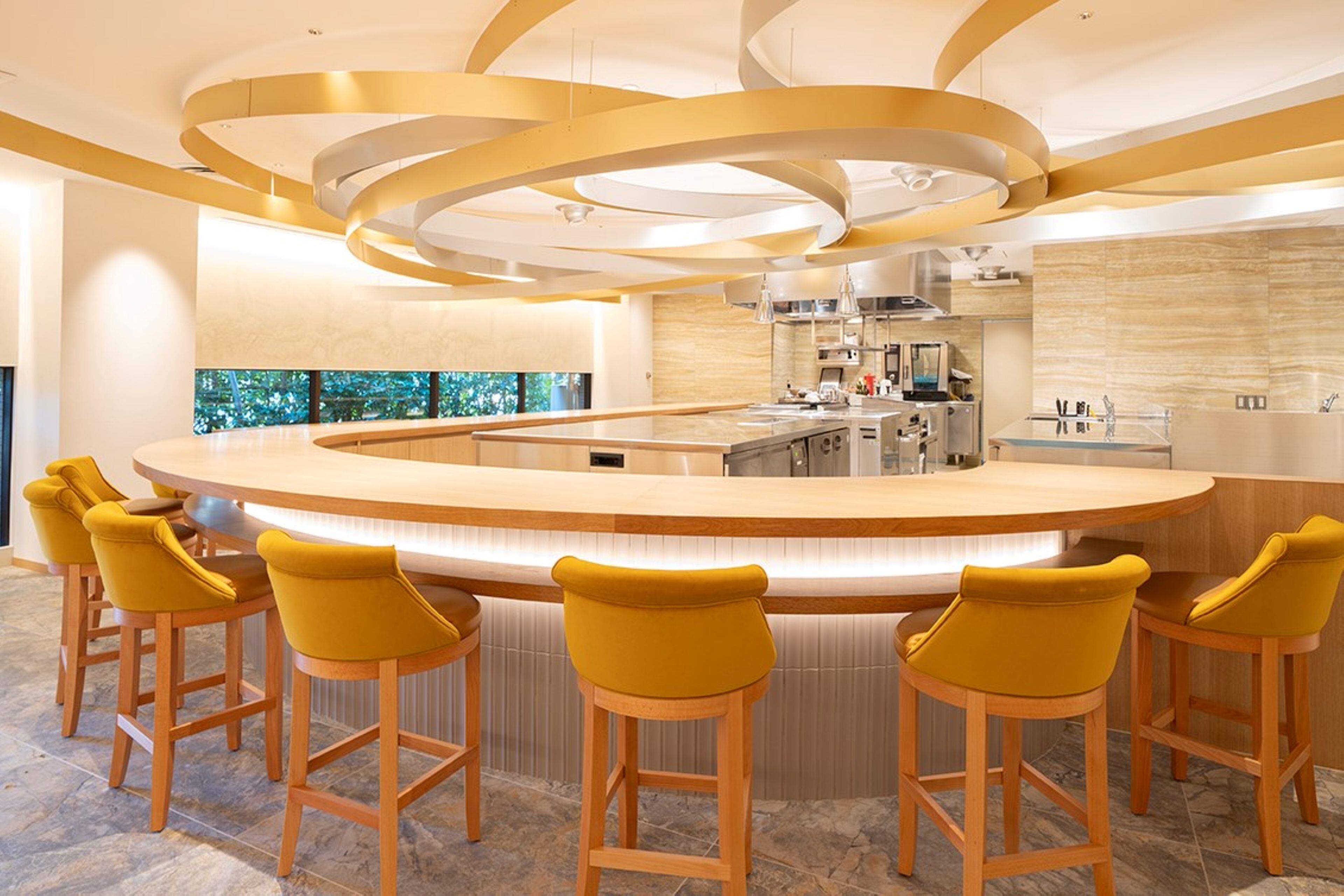 Una cocina moderna con una isla central, taburetes de bar y vistas al exterior.