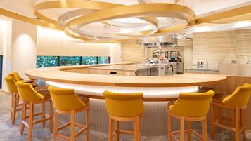 Una cocina moderna con una isla central, taburetes de bar y vistas al exterior.