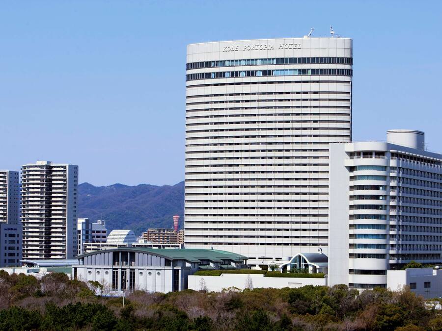 A modern hotel with a prominent cylindrical tower, multiple floors, and a flat roof.