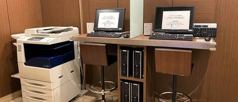 A desk with two laptops, a printer, and a computer keyboard.