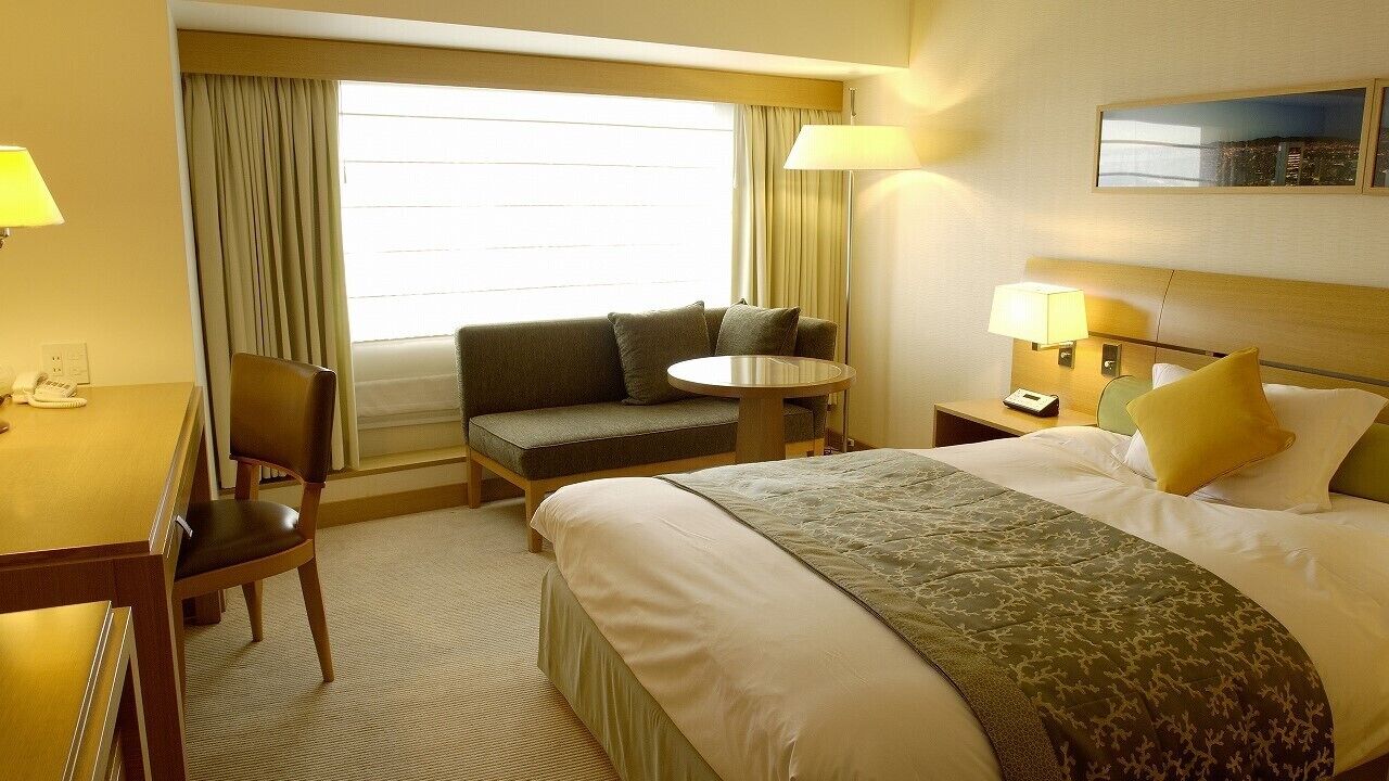 Una camera d'albergo con un letto, un divano, un tavolino, una scrivania e un comodino.