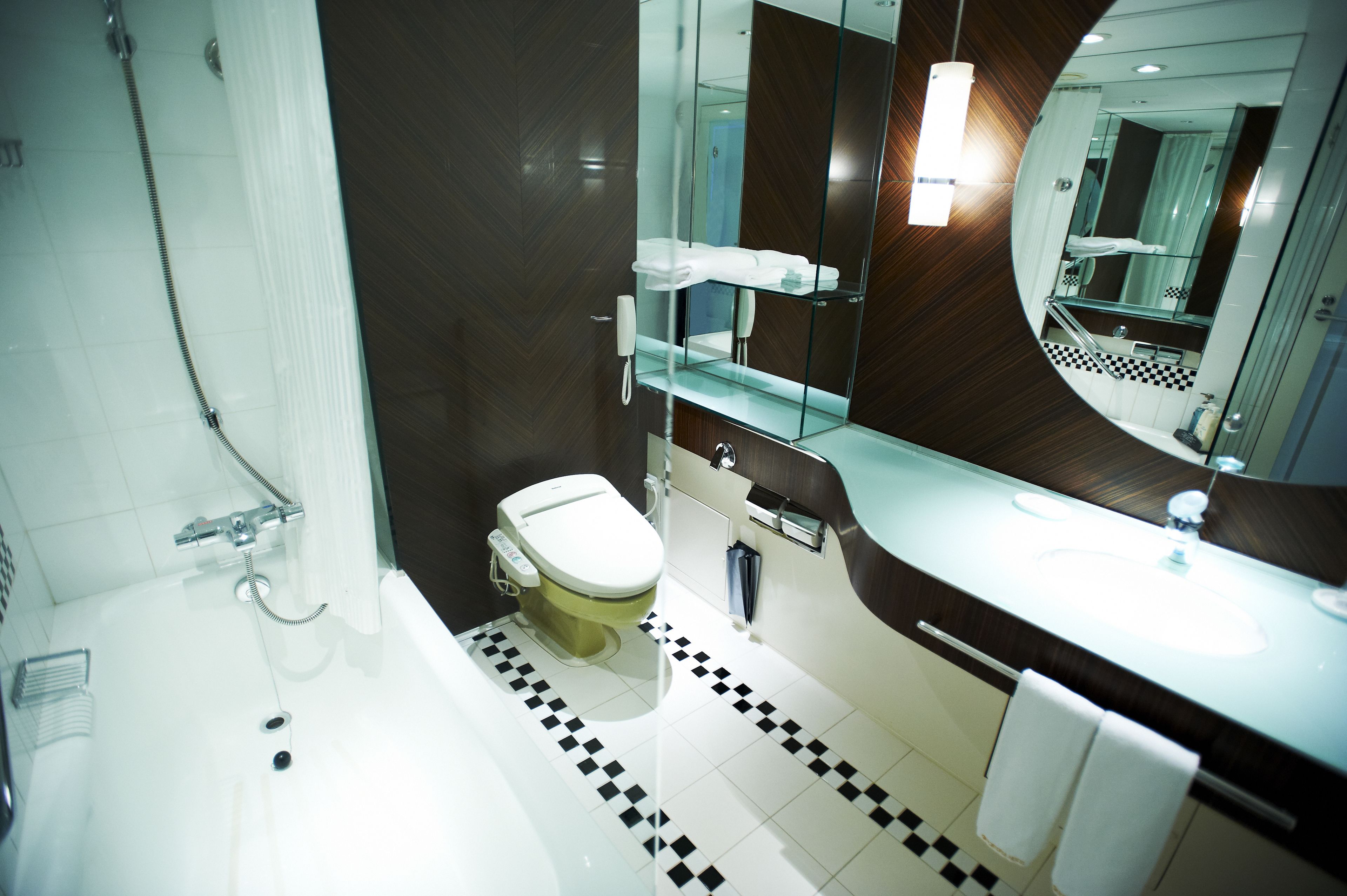 A modern bathroom with a bathtub, toilet, and a large mirror.