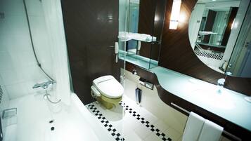 A modern bathroom with a bathtub, toilet, and a large mirror.