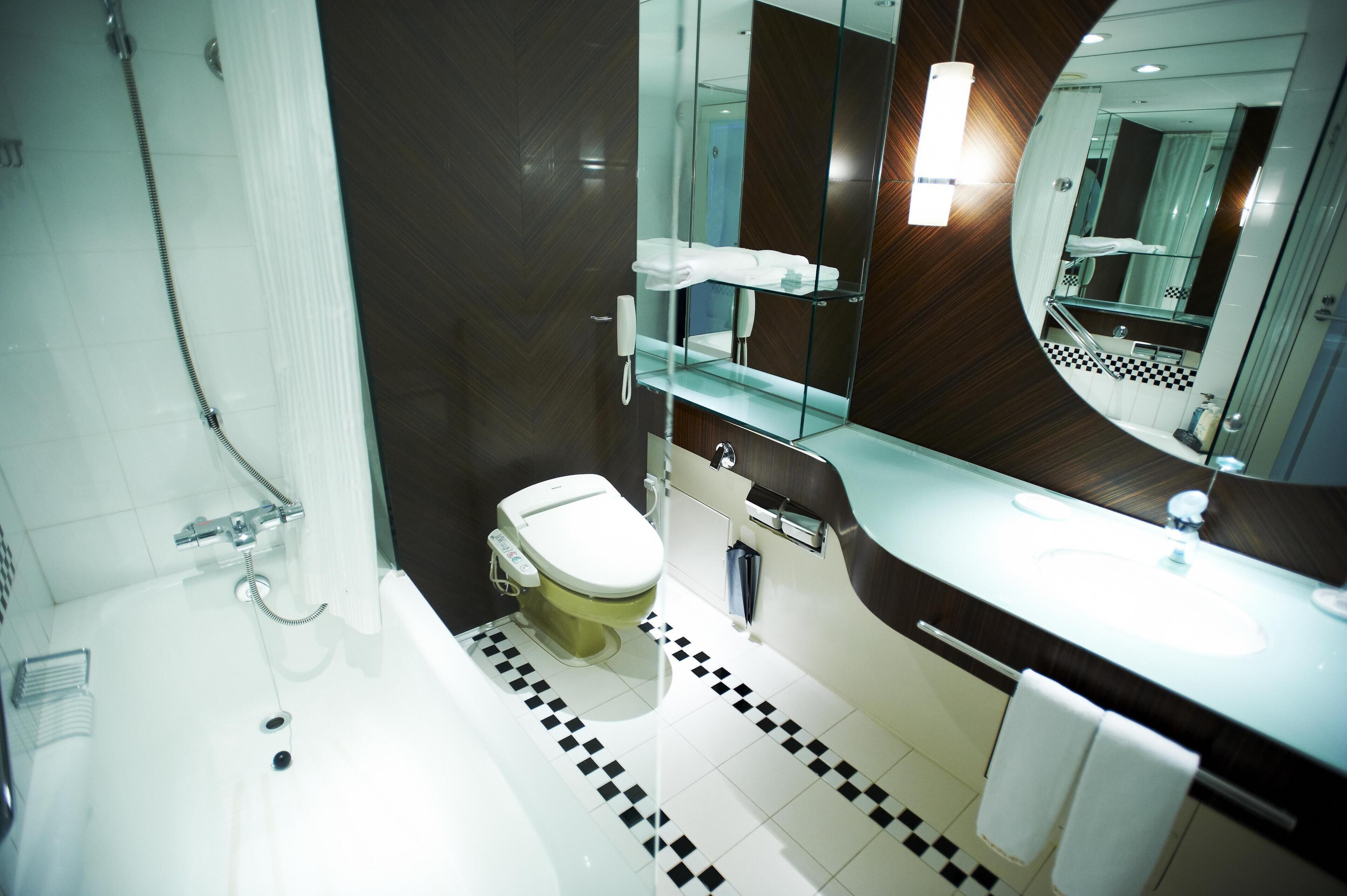 Un baño moderno con bañera, inodoro y un espejo grande.