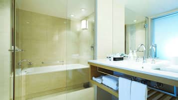 A modern bathroom with a glass-enclosed shower, a bathtub, a vanity with a mirror, and a shelf with towels.