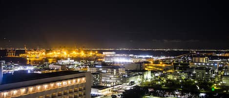 A nighttime cityscape with illuminated industrial areas and buildings.