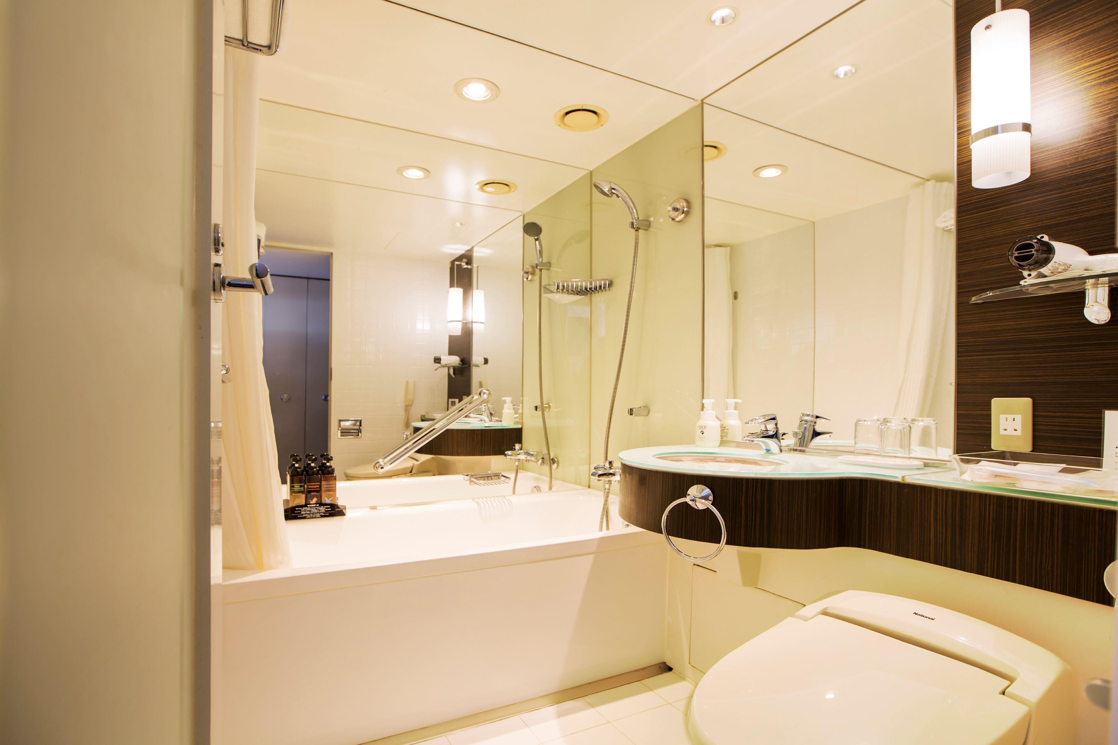 A modern bathroom with a bathtub, a toilet, a sink, and a large mirror.