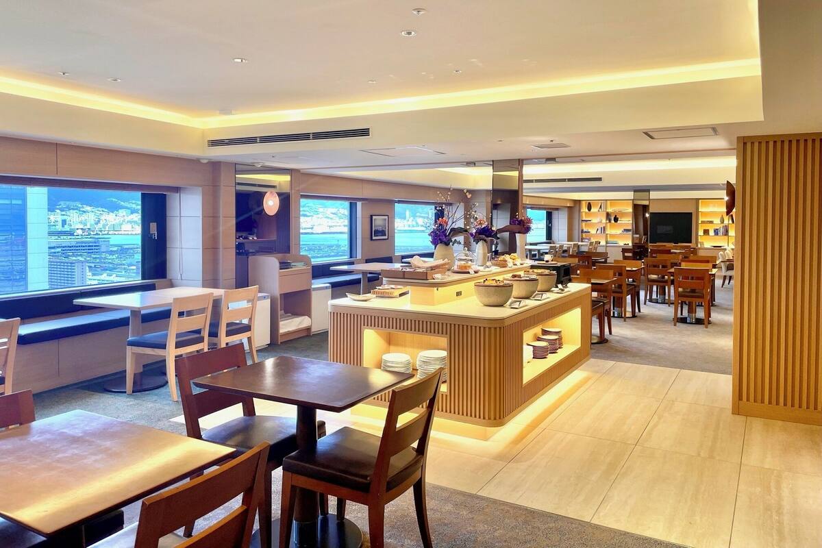 A modern hotel lobby with a central bar area, seating arrangements, and large windows offering a view of the cityscape.