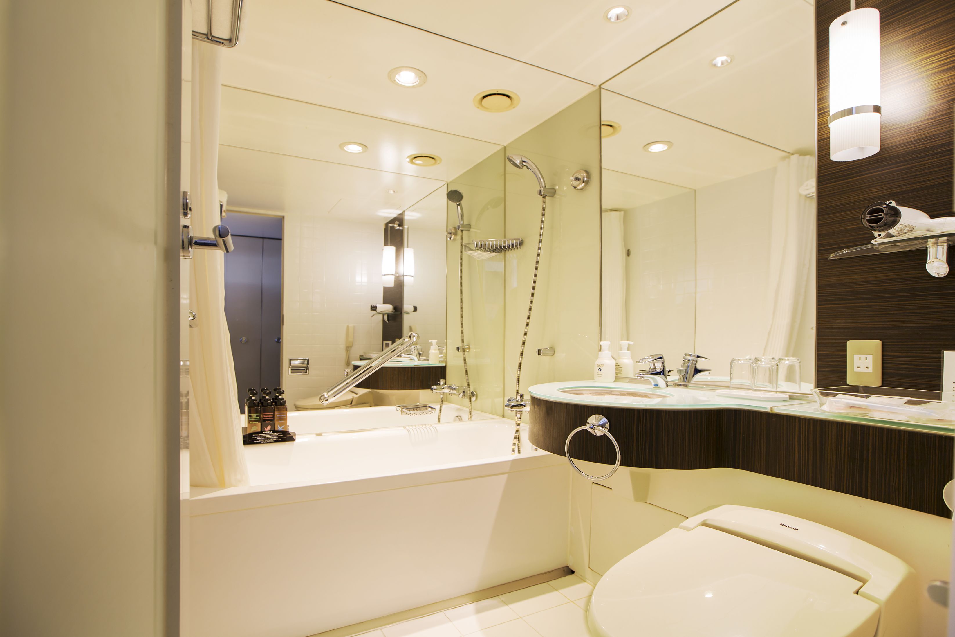 A modern bathroom with a bathtub, a toilet, and a vanity with a mirror.