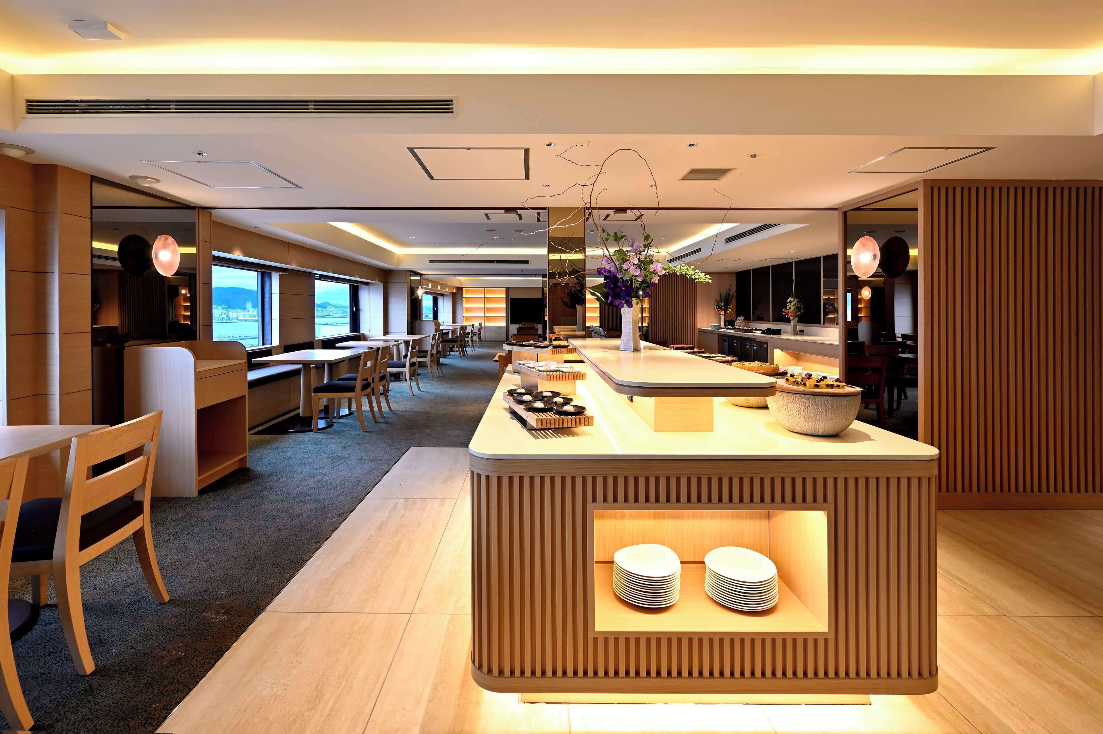 A modern hotel lobby with a central reception desk, seating area, and large windows offering views.