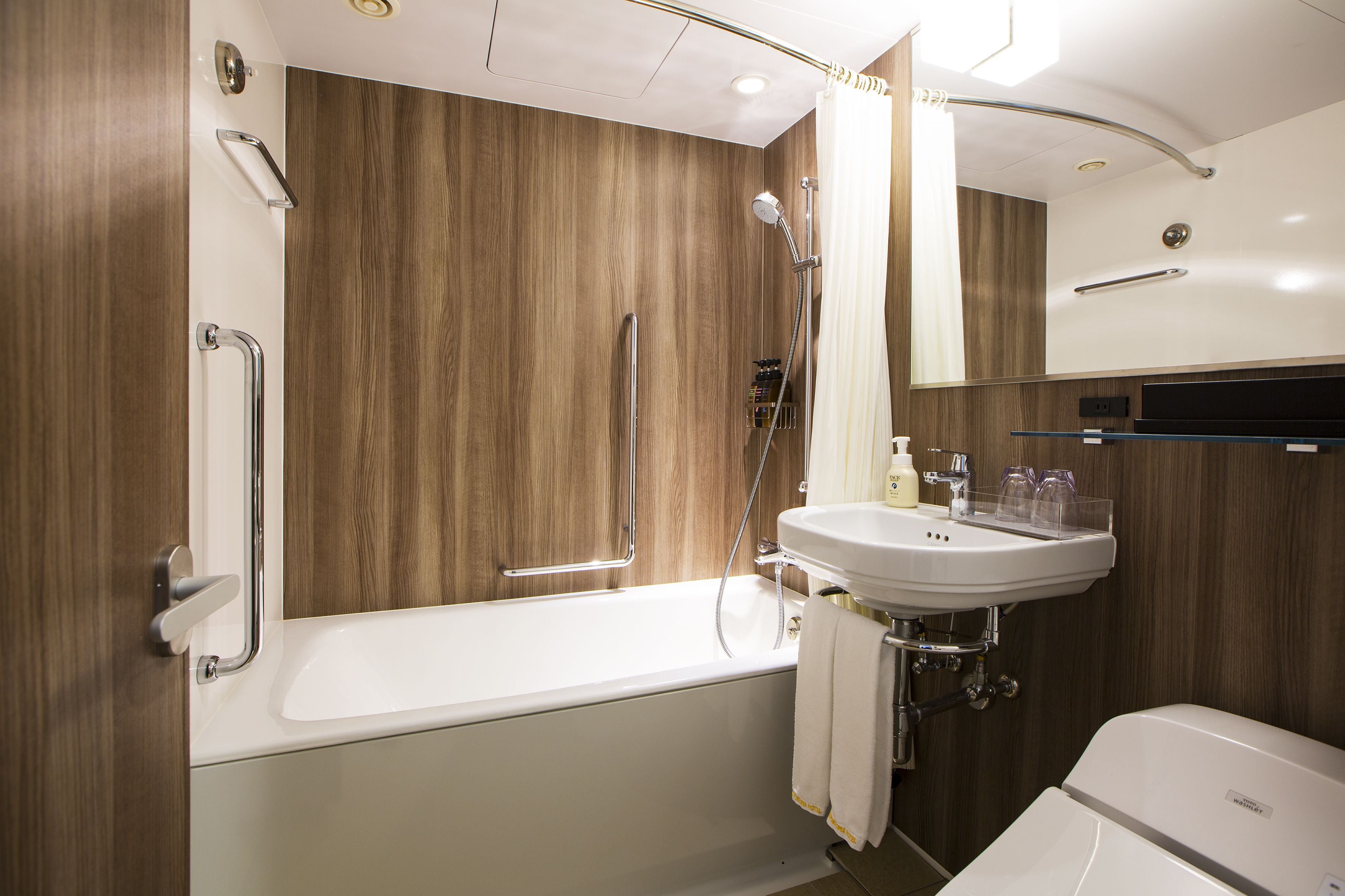 A modern bathroom with a wooden wall, a white bathtub, a sink with a mirror above it, and a showerhead.