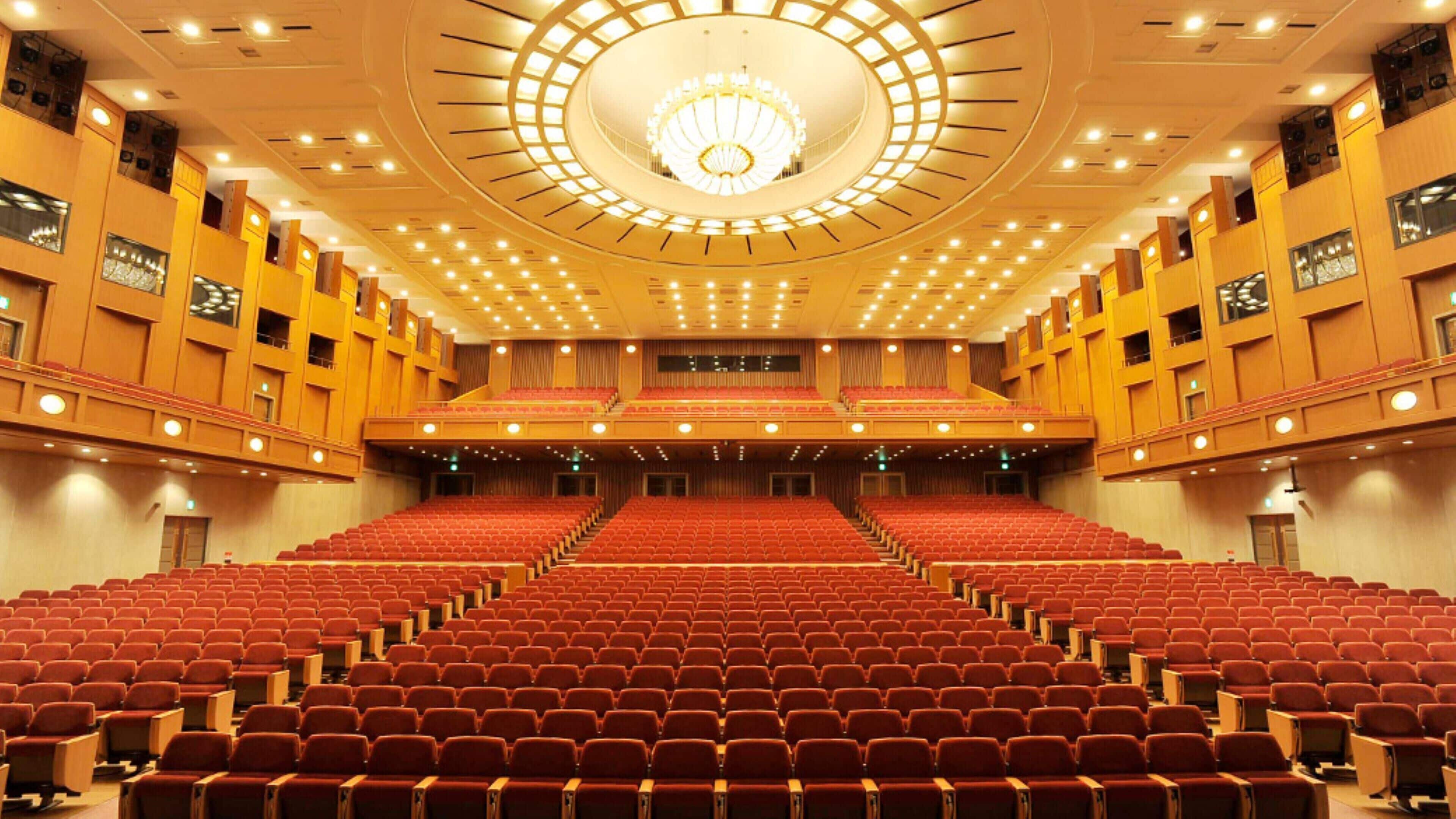 Un gran auditorio con asientos escalonados, un escenario central y un diseño de techo circular.